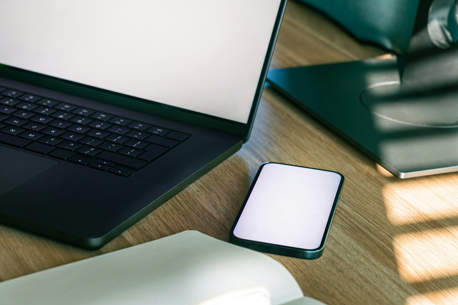 Ordinateur portable et téléphone posés sur un bureau en bois
