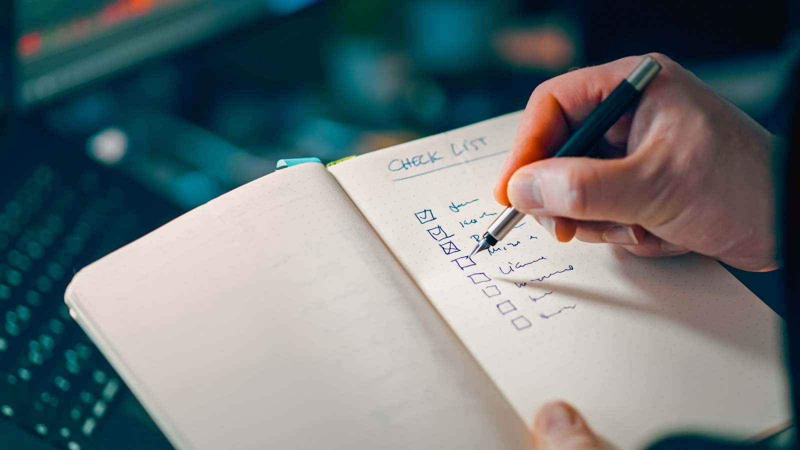 Main cochant une liste manuscrite dans un carnet