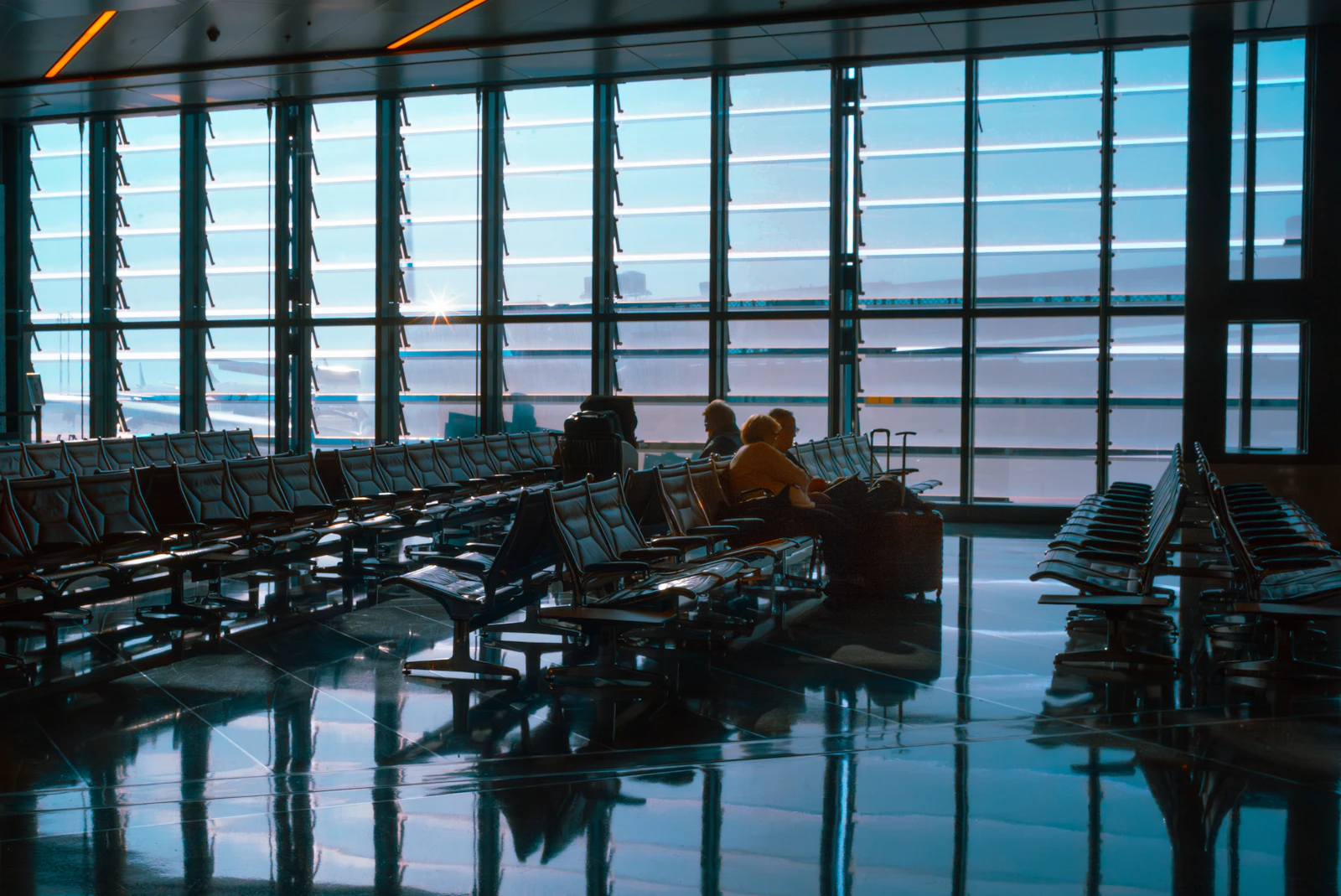 Voyageurs dans un terminal, éclairés par la lumière naturelle des baies vitrées